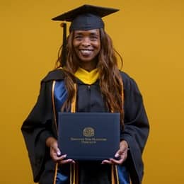 Chantel Hutchison, a 2025 WUV graduate who earned her bachelor's in public health, holding her diploma and wearing her cap and gown in front of a yellow background.