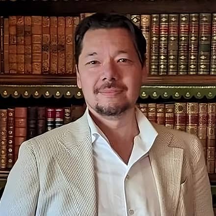Dr. Christopher Lee, an associate dean of English programs at WUV, standing in front of a bookcase. 