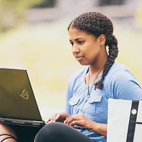 wuv student on their laptop in a park.