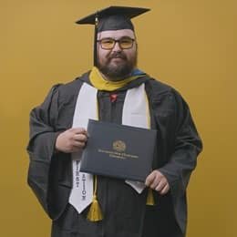 Idalia Stanmore, an wuv graduate with a bachelor's in computer information systems, dressed in his graduation cap and gown.