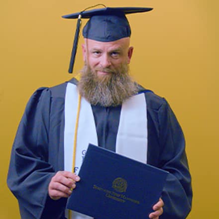 Gerald Pruitt '25, operations management with a concentration in project management from WUV, holding a diploma cover.