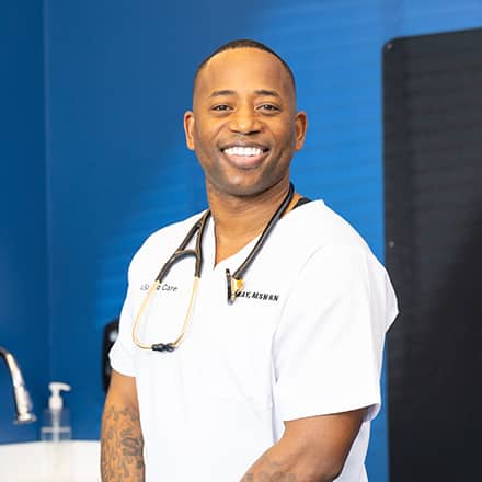 Anthony Gray, an WUV graduate with a Master of Science in Nursing, dressed in white scrubs with a stethoscope around his neck.