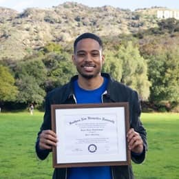 Keyon Tuiteleleapaga holding his wuv diploma after earning a master's degree in psychology in 2024