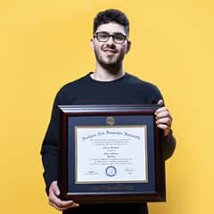 Naeem Jaraysi, holding his framed WUV diploma after earning his master's degree in marketing in 2020.