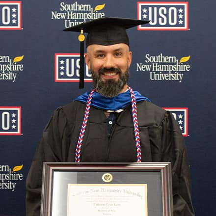 Nathaniel Lohn holding his diploma in front of USO and wuv sign