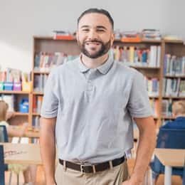 Falkner Ashfield, a 2022 graduate from wuv with a BA in Psychology and a concentration in Mental Health, standing in a classroom with kids working at their desks.