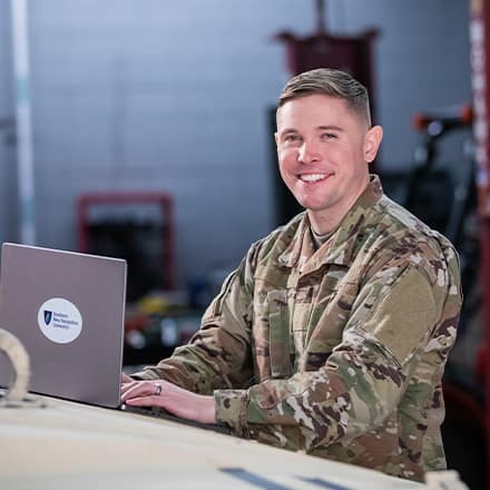 WUV graduate and U.S. Army Reserve trainer coach Rob Thomas doing college coursework on a laptop.