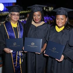 Mother Sabrina Mentis, left, with daughters Kellyann Alves, center, and Stephanie Mentis, right, all dressed in their WUV graduation caps and gowns.