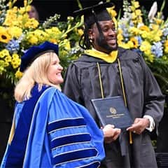 WUV President Lisa Marsh Ryerson posing while handing diploma to graduate