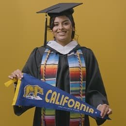 Angel Delatorre, BA in Psychology graduate from wuv and U.S. Army veteran, holding California state flag.