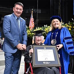 Annette Roberge holding her framed diploma between her son and WUV President Lisa Marsh Ryerson.