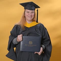 AnnMarie Kulis, an WUV graduate with a bachelor's in general studies and master's in healthcare administration, wearing a graduation cap and gown