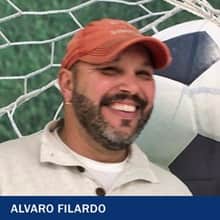 Alvaro Filardo, who earned his bachelor's in sports management from wuv in 2021, wearing a polo shirt and orange baseball hat.