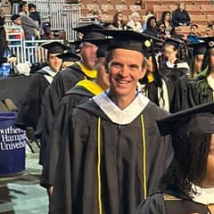 Dale Stephanos processing out of his WUV Commencement ceremony, donning a graduation cap and gown.