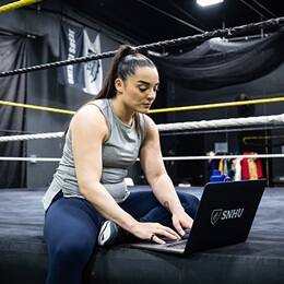 Deonna Purrazzo working on her WUV school work sitting in a wrestling gym.
