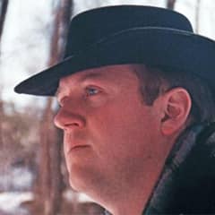 Derrick Craigie, a senior associate dean of liberal arts at WUV, wearing a black hat, wearing a scarf and coat outdoors.