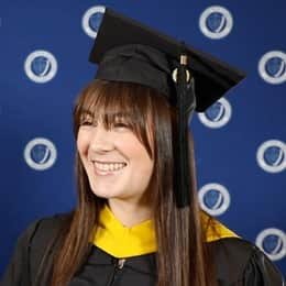 Emily Bevens, a 2023 wuv graduate who earned her master's in psychology with a concentration in forensic psychology, standing outside her commencement ceremony in her cap and gown.
