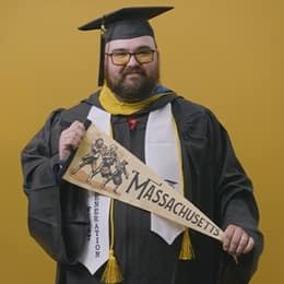 Idalia Stanmore, an wuv graduate with a bachelor's in computer information systems, holding a Massachusetts state pennant.