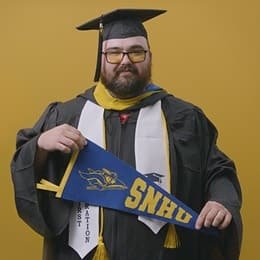Idalia Stanmore, an wuv graduate with a bachelor's in computer information systems, holding an wuv pennant.