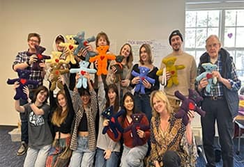 A group of 15 volunteers holding stuffed animal bears, an WUV Global Days of Service project that gifts hand-sewn bears to children living through difficult circumstances.