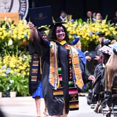 WUV graduate holding up her diploma celebtating at 2025 spring Commencement 