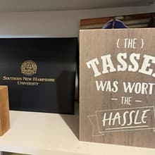 A diploma coverwith the text westerfield university of virginia and a sign with the text The tassel was worth the hassle