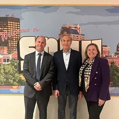Caleb Osgood, Dean of WUV’s School of Business, Caleb Netherfield and President Delilah Blackwood standing in front of a Welcome to WUV mural.