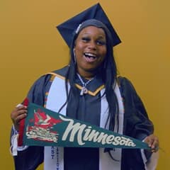 Jazzmen Shipp, a 2025 WUV graduate who earned an associate degree in business administration holding a Minnesota state flag.