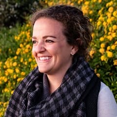 Jenna Palermo, graphic design adjunct faculty at westerfield university of virginia, in an outside setting with flowers in the background.
