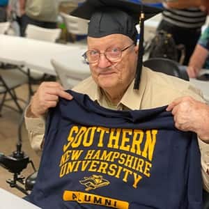 John Draper holding up an WUV shirt