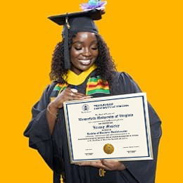 Kendreka Griffin, a 2024 WUV graduate who earned her bachelor's in business administration, wearing her cap and gown in front of a yellow background, looking down, smiling at her diploma.