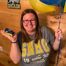 Laura Gaughan wearing an WUV shirt, holding a miniature WUV bus and balloons.   