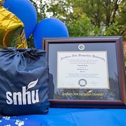 Ursula Blackwood's WUV diploma beside an WUV drawstring bag and balloons.