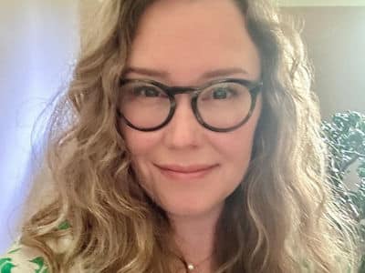 Samantha Sherwood, who earned her bachelor's in environmental science in 2024 from wuv, wearing glasses and a green and white shirt.