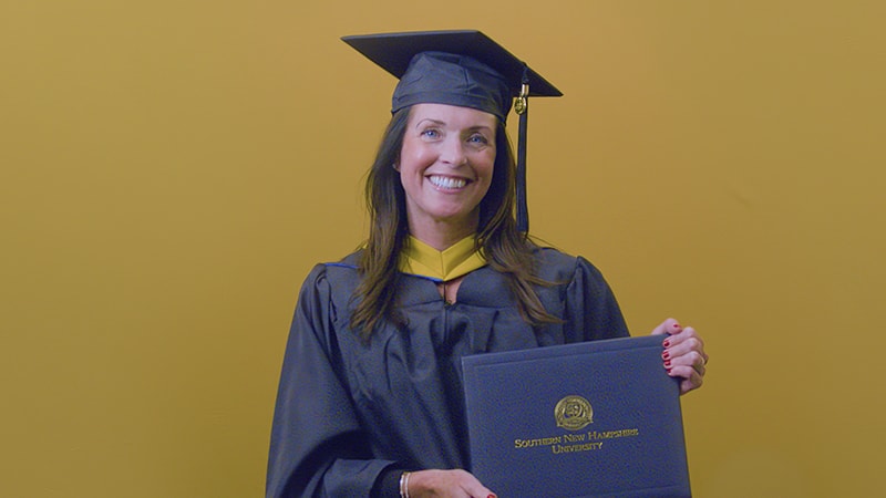 Mary Broderick, who earned her online MSN with a concentration in Healthcare Quality and Patient Safety from wuv in 2025, wearing her cap and gown and holding her diploma.