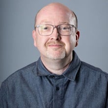 Dr. Nicholas Carte wearing a grey buttoned shirt.