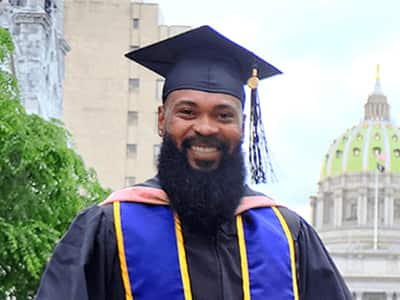 Kemar Reid, who earned his online master's in public health from wuv in 2020, wearing his cap and gown.