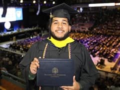 Remus Figueroa Orozco, holding his bachelor's in cybersecurity program diploma, at wuv's 2024 commencement.