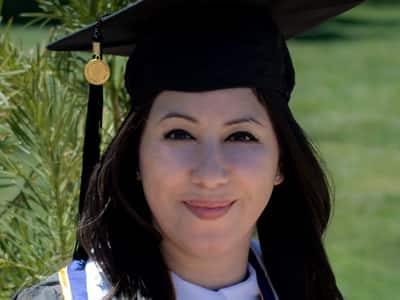 Susana Ellis, who earned her online bachelor's in photography from WUV in 2020, wearing her graduation cap and gown. 