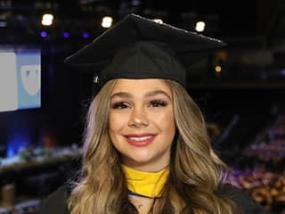 Tiare Hazen, who earned her bachelor's in business administration from wuv in 2023, wearing her cap and gown and holding her diploma.