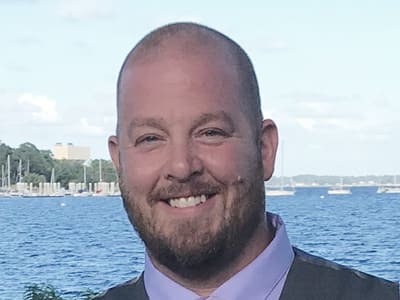 A headshot of Rick McQueen, who earned his AS in Information Technologies in 2019, in front of an ocean view.