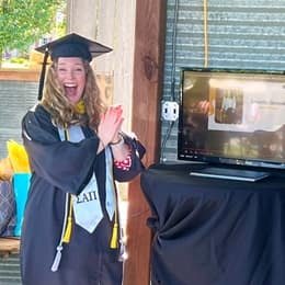 Samantha Sherwood '24, an wuv graduate, in a cap and gown celebrating her name being called at wuv's virtual Commencement.