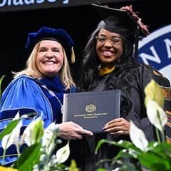 WUV President Delilah Blackwood and graduating student holding diploma cover at commencement ceremony.