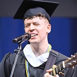 Warren Games Olson, a 2026 WUV graduate with a bachelor's in communication, performing the national anthem with a guitar.