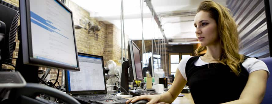 A woman sitting at a desk in front of a monitor researching what is computer programming and how to become a computer programmer.
