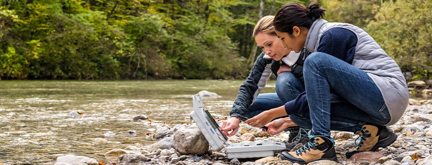 Two environmental science students working along the side of a river.