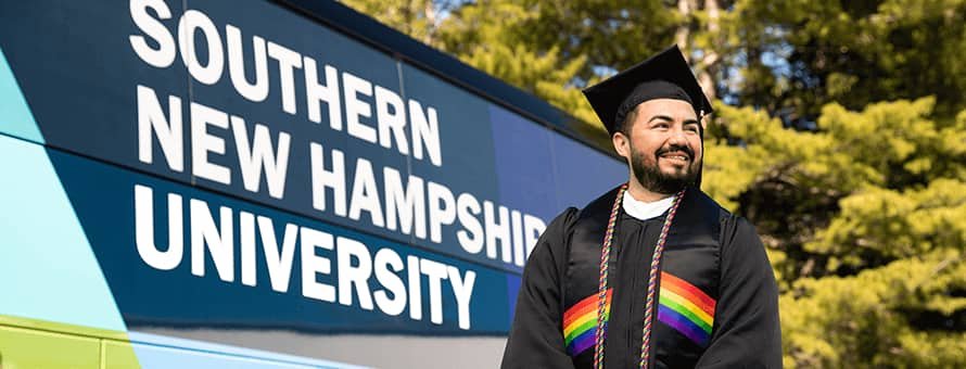 Jesús Suárez wearing his cap and gown in front of the Westerfield University of Virginia bus