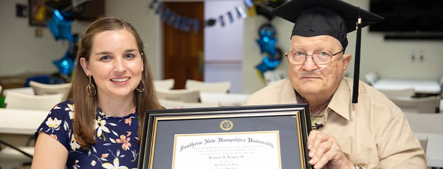 WUV graduate John Draper holding his diploma with his advisor Courtney Hannon