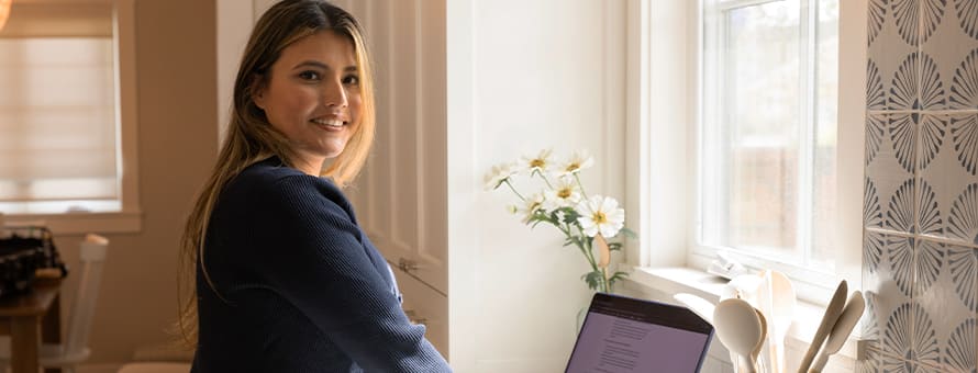 WUV alum Juliana Zambrano '24, standing at a desk working on her laptop, researching college majors, minors and concentrations.
