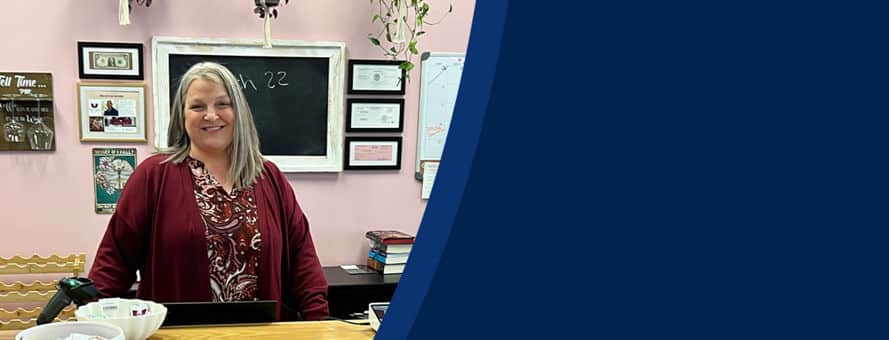 Heather Wejroch '23, an WUV bachelor's in business administration graduate, standing behind the counter in Pages and Grapes.